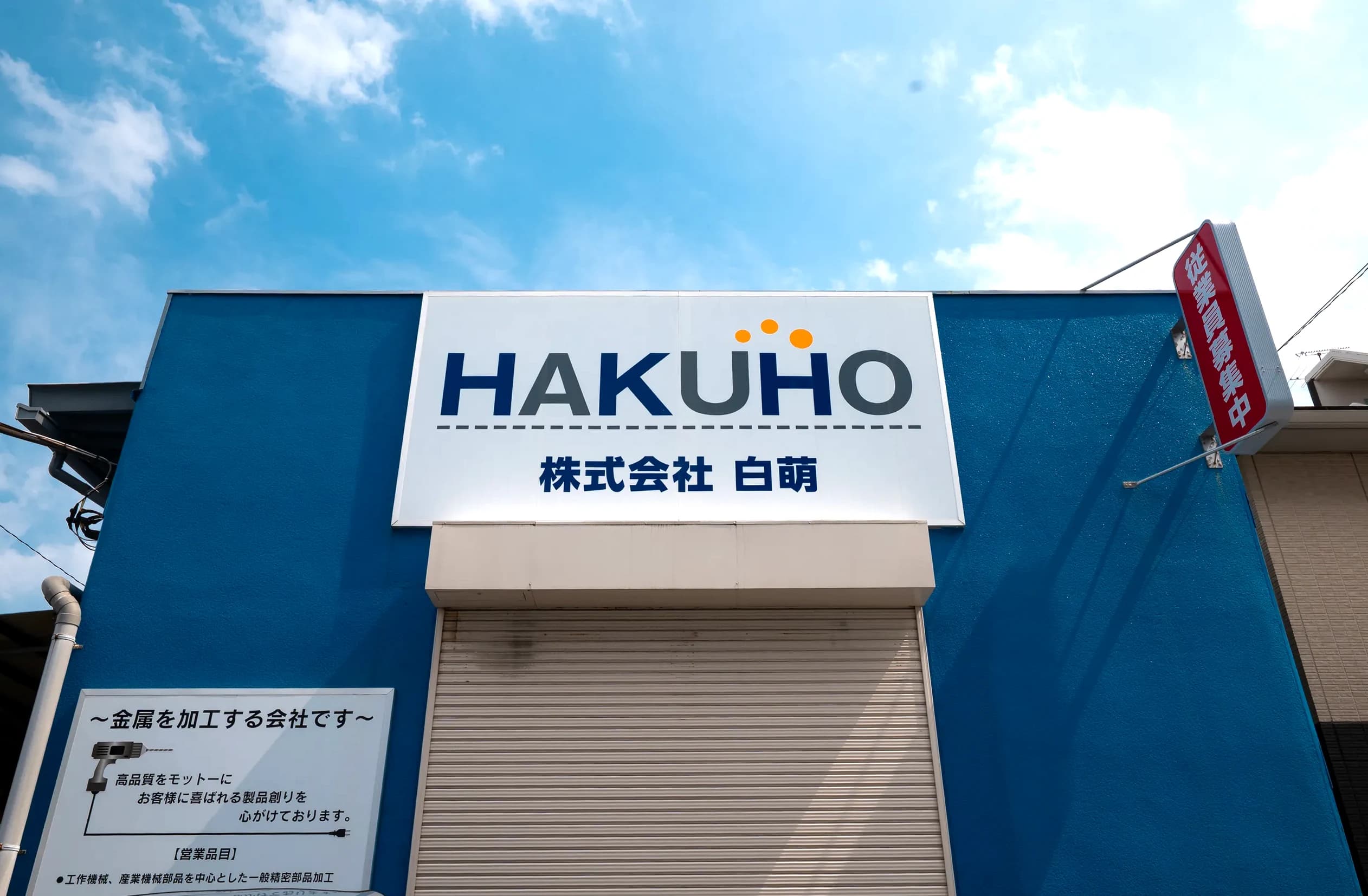 青空に映える株式会社白萌の社屋サイン